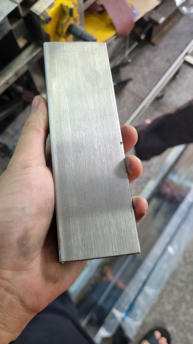 Thanh hộp inox đã đánh xước mịn cầm trên tay