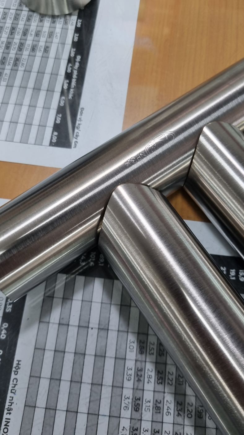 Hai ống inox cắt vát ghép khít vào nhau đặt trên bàn